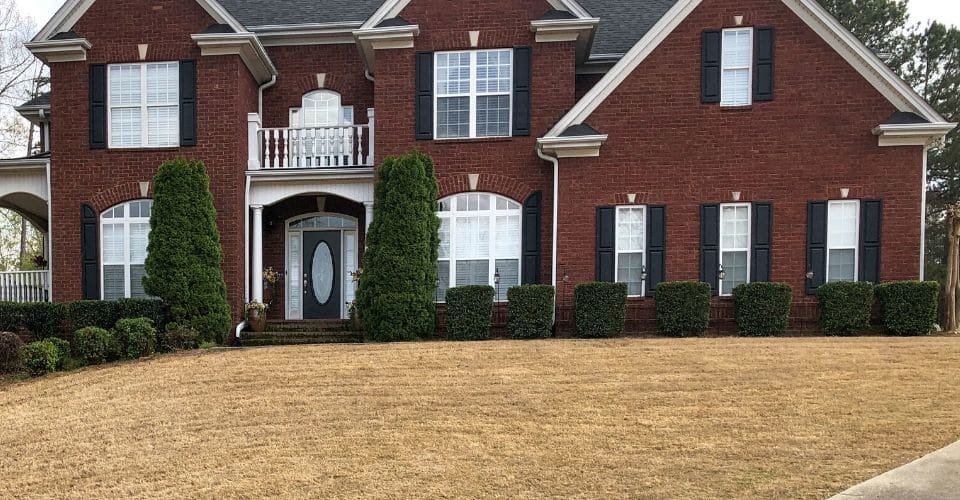 2-story residential brick home with a manicured lawn and landscape after a yard cleanup service.